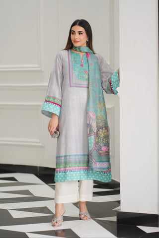 Woman wearing a light gray traditional outfit with a colorful dupatta in a modern interior setting.